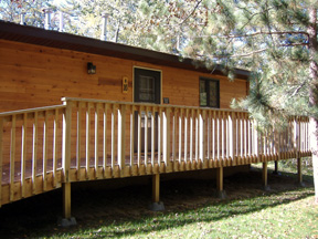 This entry door of Cabin #16 leads into the kitchen.  It is ramped from the parking area and also leads to the deck, picnic table, & BBQ grill.  Cabin #16 sits on a slight hill looking over the top of the Cabin #6 and Cabin #5.